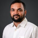 Professional portrait of a man in a white shirt against a gray background.
