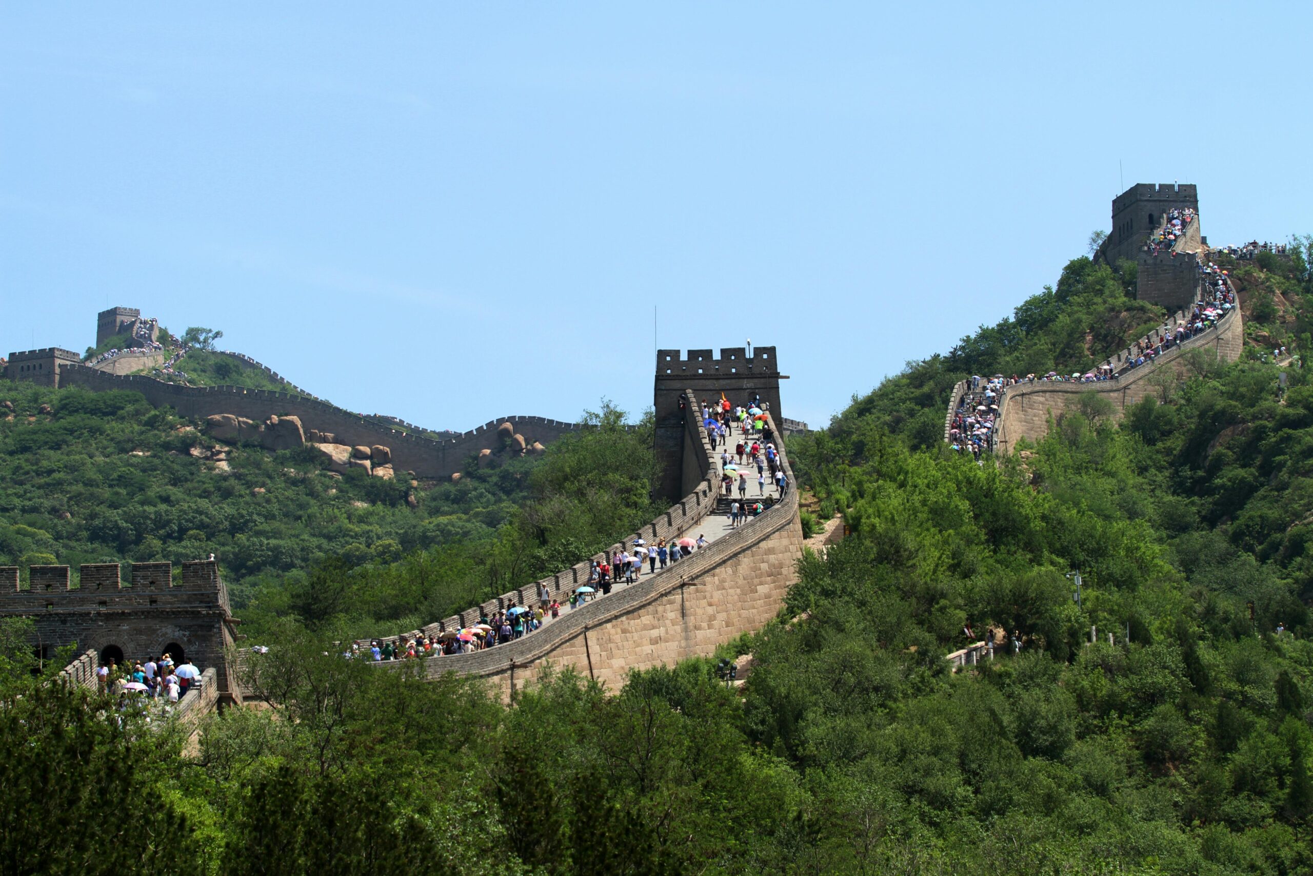 A breathtaking view of the Great Wall of China with lush greenery and historic architecture.